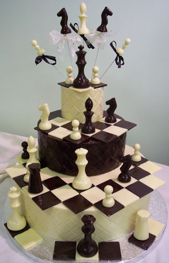 a picture of milk and white chocolate chess pieces on three chocolate tiers