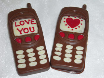 Two milk chocolate valentine mobile phones decorated with White and coloured chocolate.  One display shows a Love You message, the other a heart
