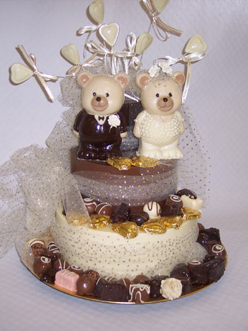 a picture of chocolate wedding teddies decorated with love hearts, truffles and ribbon, on a chocolate tier