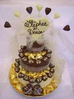 chocolate wedding tier decorated with personalized love hearts, truffles and ribbon